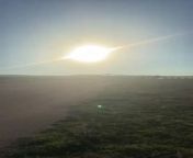A person filmed a light aircraft landing on the runway. With the sun shining brightly in the background and the aircraft approaching, created a beautiful scenic view.